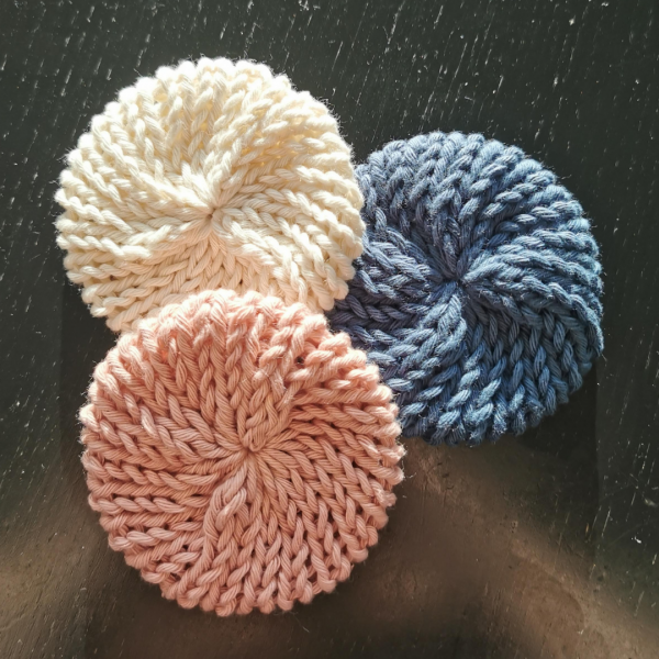 Three, different coloured, hand knite face scrubbies